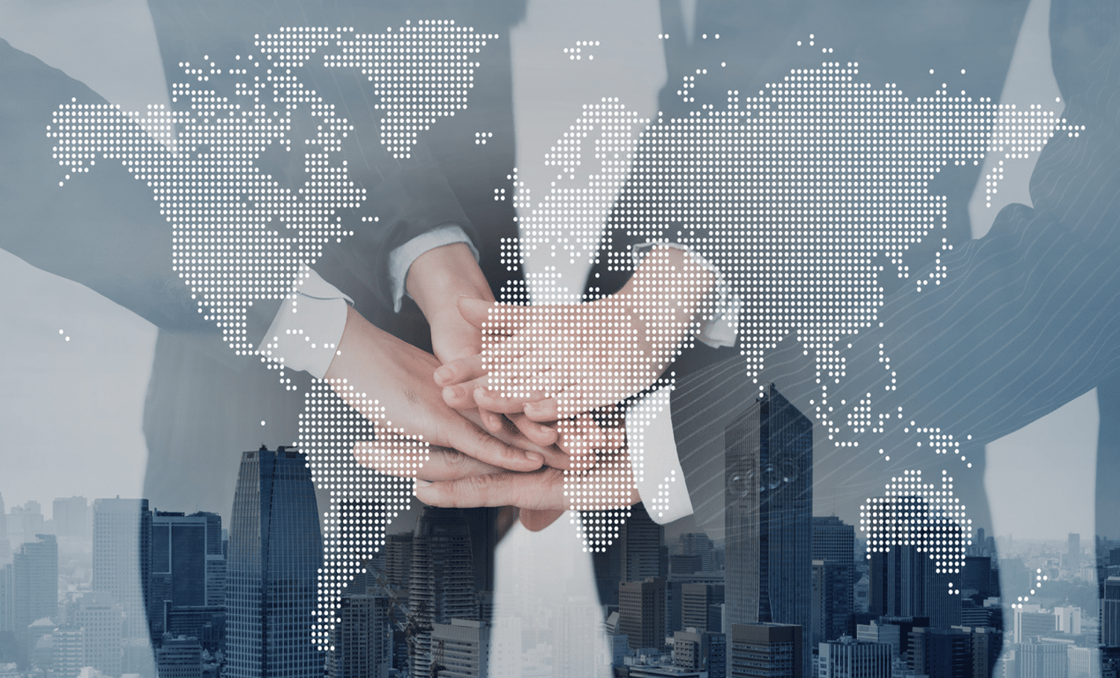 A group of business professionals place their hands together in a show of unity and teamwork. The image is overlaid with a dotted world map, symbolizing global cooperation and connection. The background features a cityscape with skyscrapers, further emphasizing the theme of international business and collaboration.